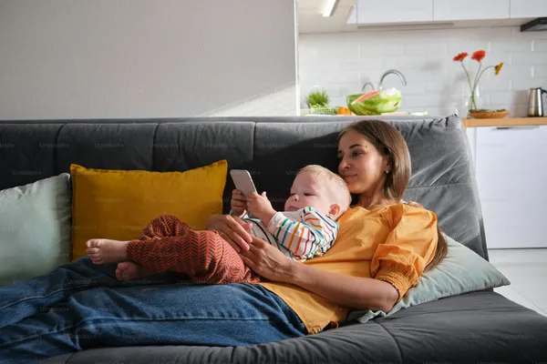 A parent and baby relaxing on the couch